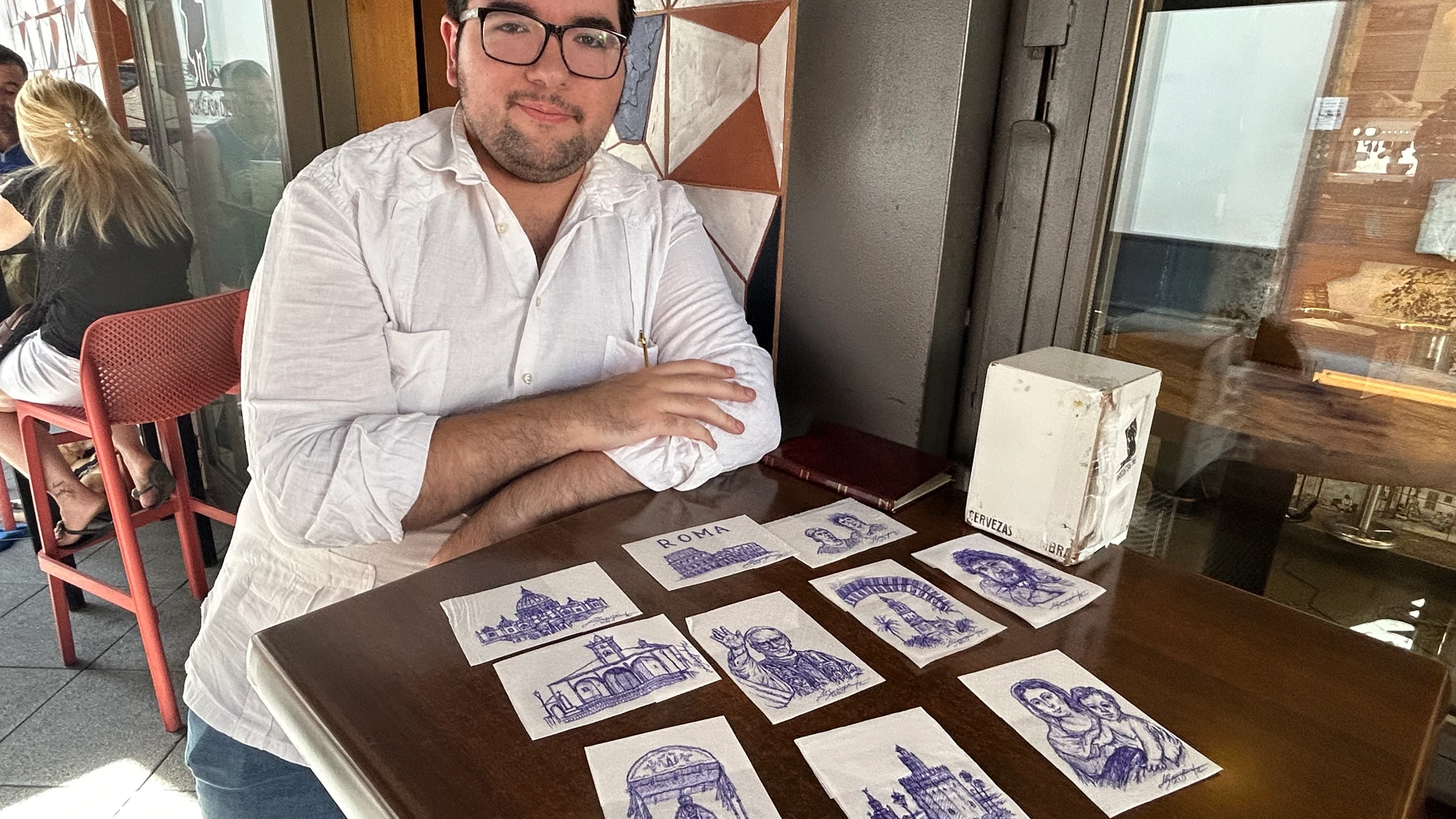SEVILLA, 20/08/2025.- Manuel Barragán, un joven sevillano de 23 años, se ha hecho famoso en los últimos días por realizar obras de arte en servilletas de los bares de su ciudad, unos dibujos que realiza en poco más de diez minutos y siempre a bolígrafo. EFE/Fermín Cabanillas