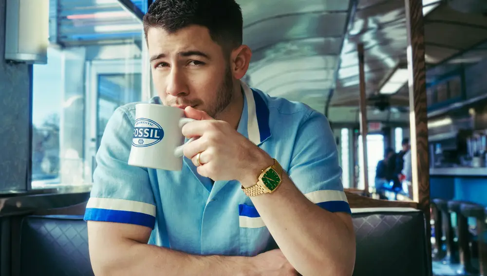 Nick Jonas en la campaña de Fossil Machine Luxe, con el reloj dorado de esfera verde.
