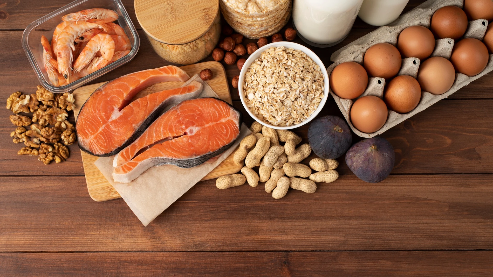 Conjunto de alimentos ricos en omega 3 como salmón, frutos secos y huevos sobre una mesa