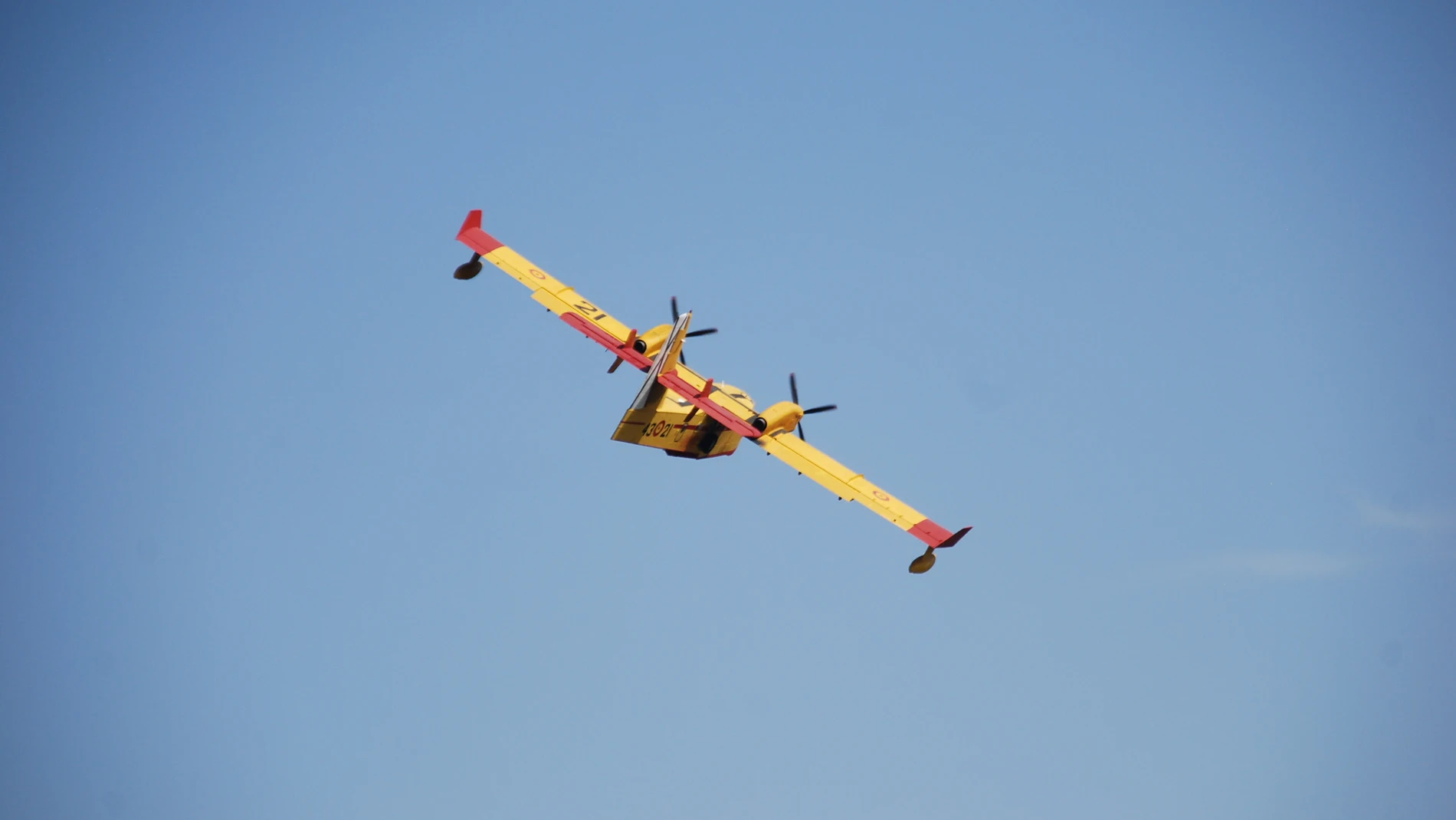 Avión de color amarillo y rojo volando en dirección a una maniobra contra los incedios