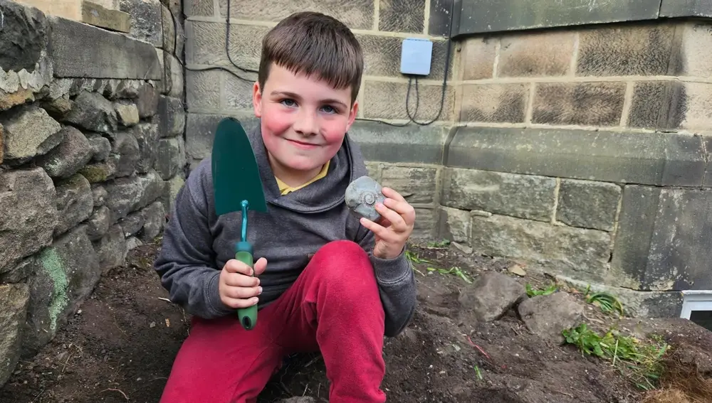 El pequeño Elliot posa junto a su descubrimiento y dice que "su fósil mola"