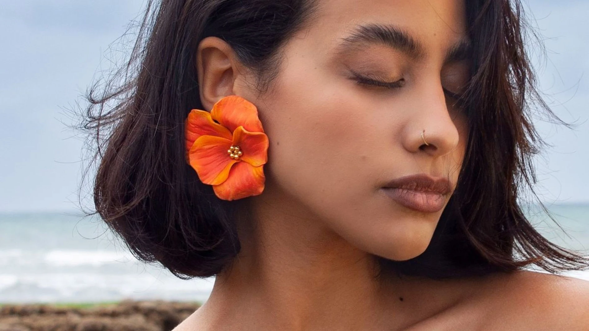 Primer plano de una mujer con los ojos cerrados en la playa, pestañas naturales tras el verano, concepto de cuidado y belleza.