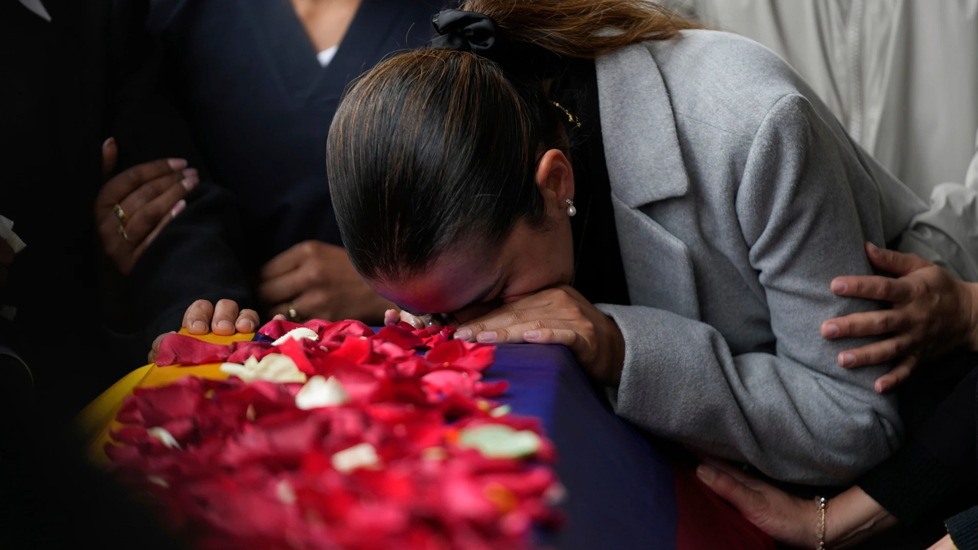 Police Maj. Adriana Pinzon kisses the coffin of her husband, Capt. Francisco Merchan, a police pilot killed when his helicopter was shot down by a dissident faction of the former FARC guerrilla group, during his burial in Mongua, Colombia, Monday, Aug. 25, 2025. (AP Photo/Fernando Vergara)
