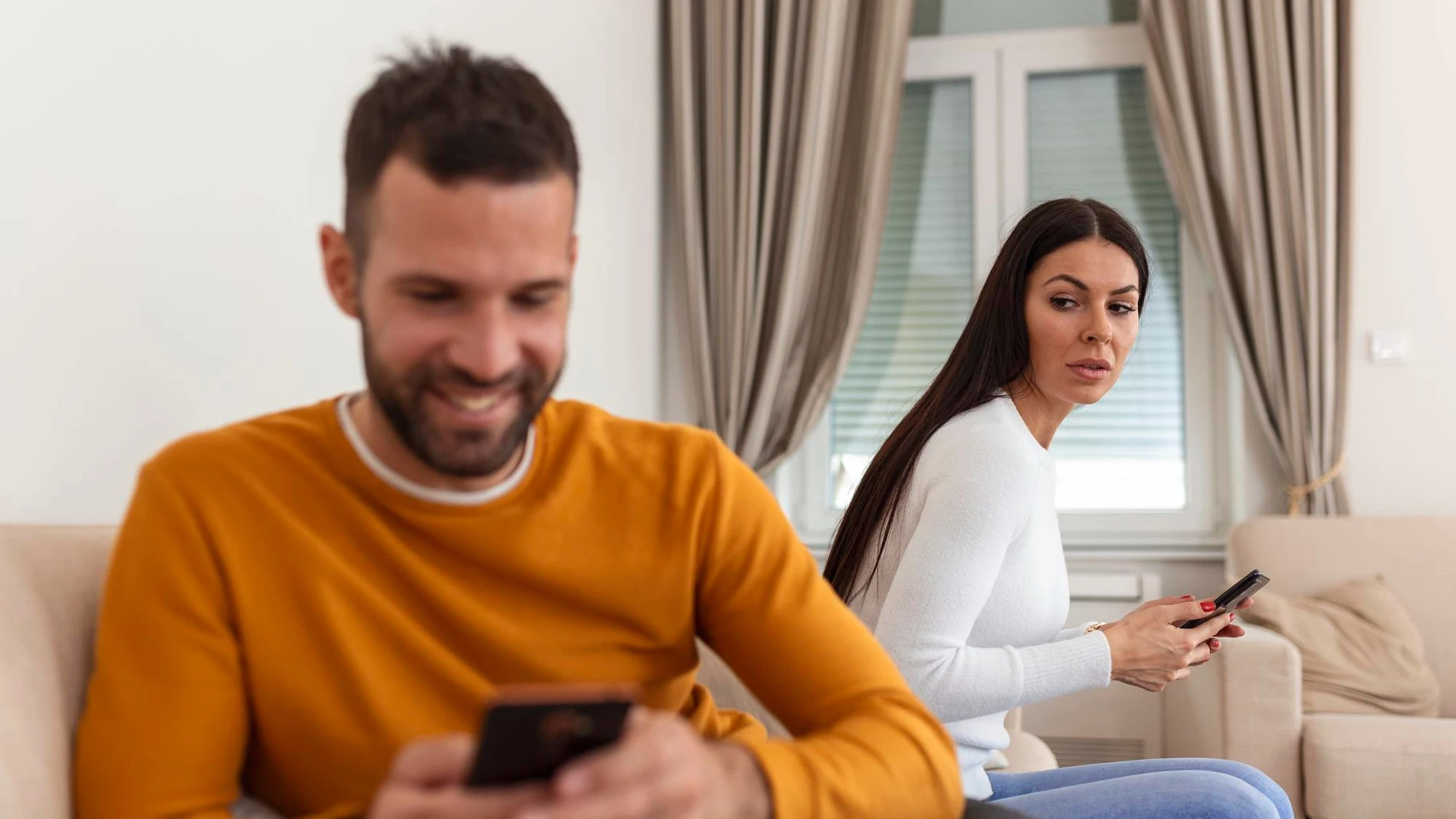Pareja en la mesa, uno de ellos distraído mirando el móvil mientras el otro se siente ignorado