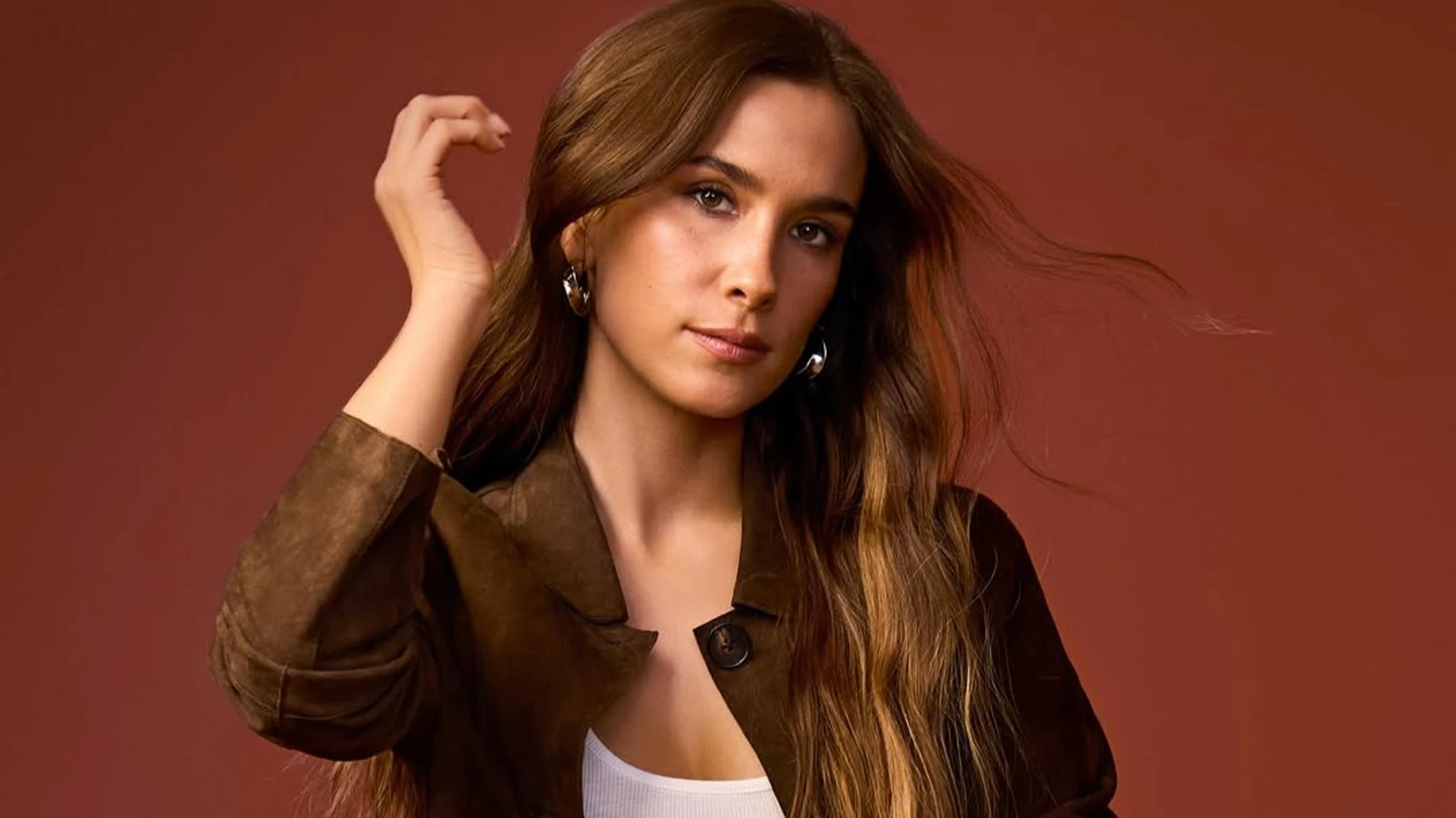 María Pombo con chaqueta de ante marrón y top blanco en un retrato de estilo otoñal.